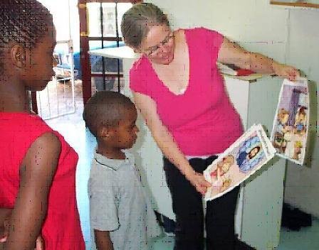 Rita (right) shows beautiful new posters that teach spiritual values and life skills.