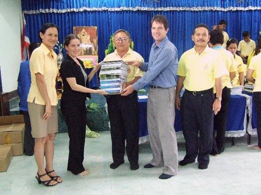 Family members distributing books to a school representative in Thailand