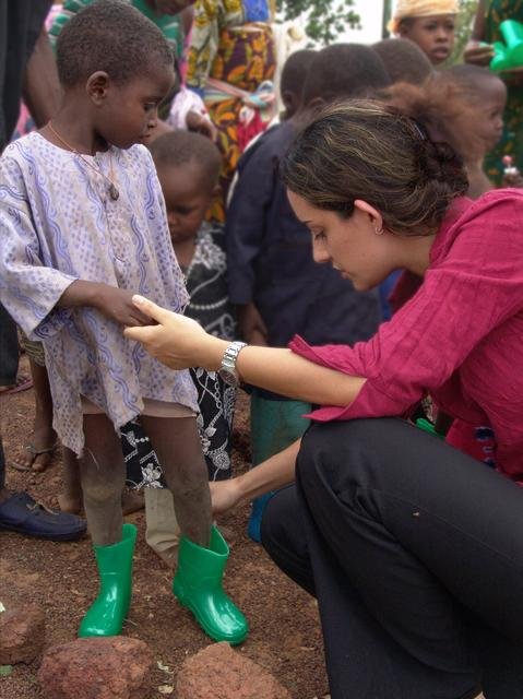 Elene, voluntaria de la Familia Internacional, entrega un par de botas nuevas a un niño necesitado