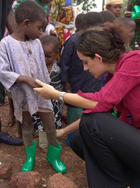 Family Volunteer Elene fits a new pair of rain boots on one of the underprivileged recipients