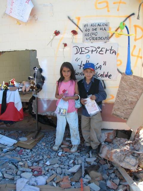 Children posing with their gifts next to a makeshift altar for people crushed by their collapsed apartment building